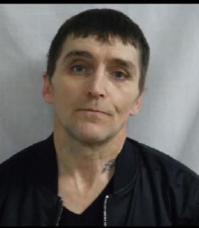 Man with short dark hair and a slight smile, wearing a black jacket.
