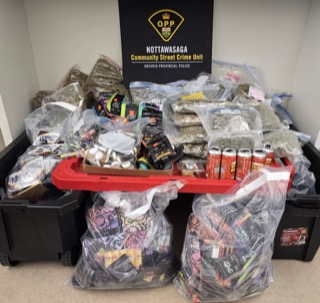 Large quantity of seized items in black and clear plastic bins.