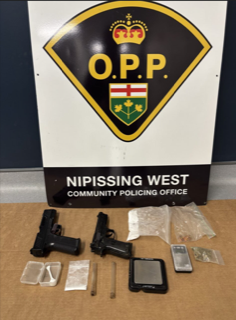 Two handguns, baggies, and a scale on a surface.