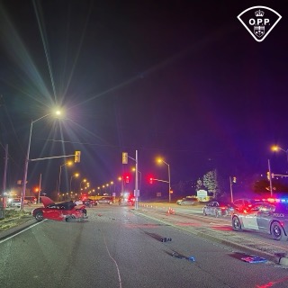 Vehicle wreckage on a dark road, police lights flashing