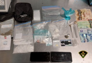 Assorted drugs in plastic bags, a pipe, and Canadian currency on a surface.