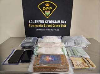 Stacked packages of cash and several cell phones on a table.