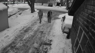 Two people walking on snow-covered street