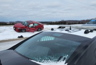 Red car in snow, damage visible 
