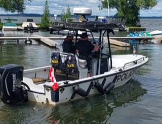 Police boat with two officers, Canadian flag, Evinrude engine