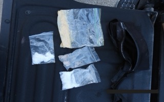 Small baggies taped to a black surface.