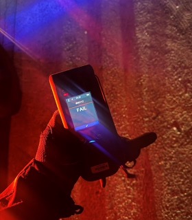 Hand holding a phone displaying 23:23 and the word FAIL