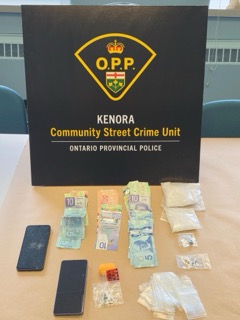 O.P.P. logo, KENORA Community Street Crime Unit, ONTARIO Provincial Police. Canadian currency and a smartphone on a table.