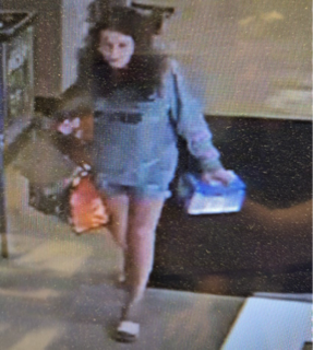 Person walking, wearing a gray hoodie and denim shorts.