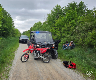 Dirt bike and side-by-side ATV on a gravel road, officers present