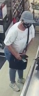 Person wearing a gray baseball cap, white t-shirt, and jeans. They are holding a black bag over their shoulder.