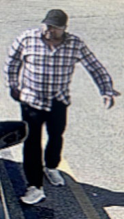 Person in a plaid shirt and dark pants walking.