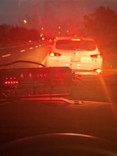 Rear of a white SUV with brake lights illuminated, blurry background