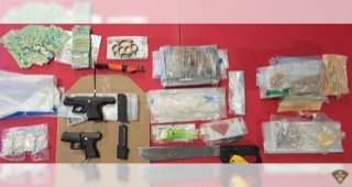 Canadian twenty-dollar bills, packages of suspected drugs, two handguns with magazines, knives, and a red fire extinguisher.