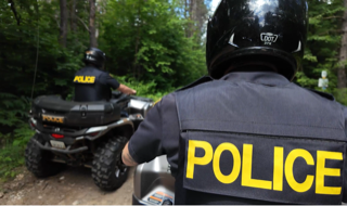 Police officer on a motorcycle in a wooded area.
