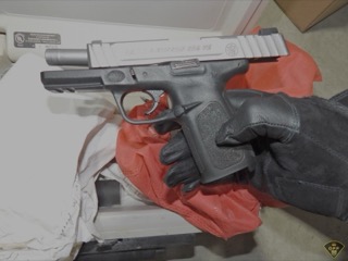 Black handgun on a surface with gloves