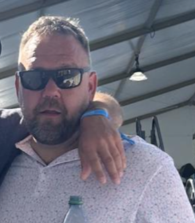Man with sunglasses and a beard, wearing a patterned shirt