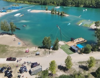 Aerial view of a wakeboarding lake with people on the water and shoreline.