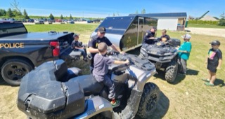 Police officers and children near an ATV.