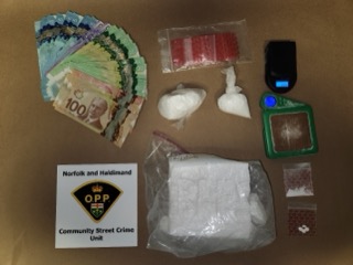 Canadian currency and white powder, small baggies, digital scale, and a badge that reads: Norfolk and Haldimand Community Street Crime Unit.