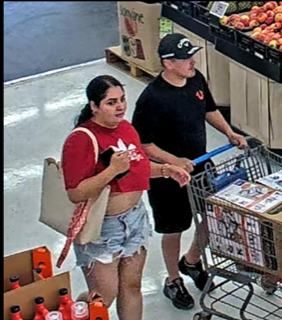 Two people in a grocery store, one pushing a shopping cart.