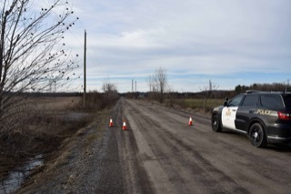 A police SUV blocks a muddy road.