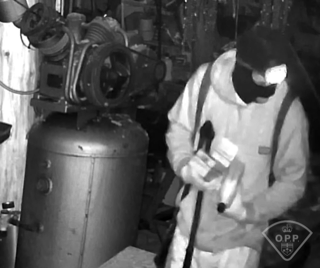 Person in a protective suit standing near a large tank.