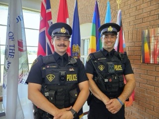 Two police officers in uniform smiling at the camera.