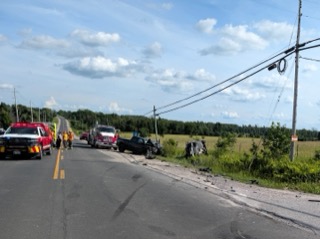 Damaged vehicles and emergency responders on a two-lane road.