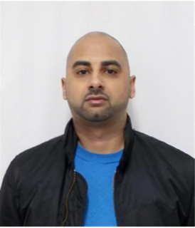 Bald man with a goatee, black jacket, blue shirt