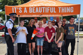 Group of people and a police officer under an orange tent. It’s a beautiful thing