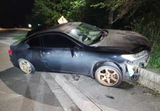 Damaged black sedan on the side of a road