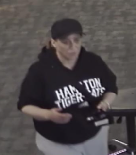 Person wearing a black hooded sweatshirt with &quot;Han Tiger&quot; printed on it, white pants, glasses.