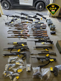 Numerous firearms and ammunition in plastic bags.