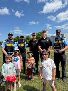 Four police officers and four children stand outdoors.